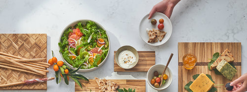 display of four cutting boards with salad, cheese, fruits, vegetables, and bread on top