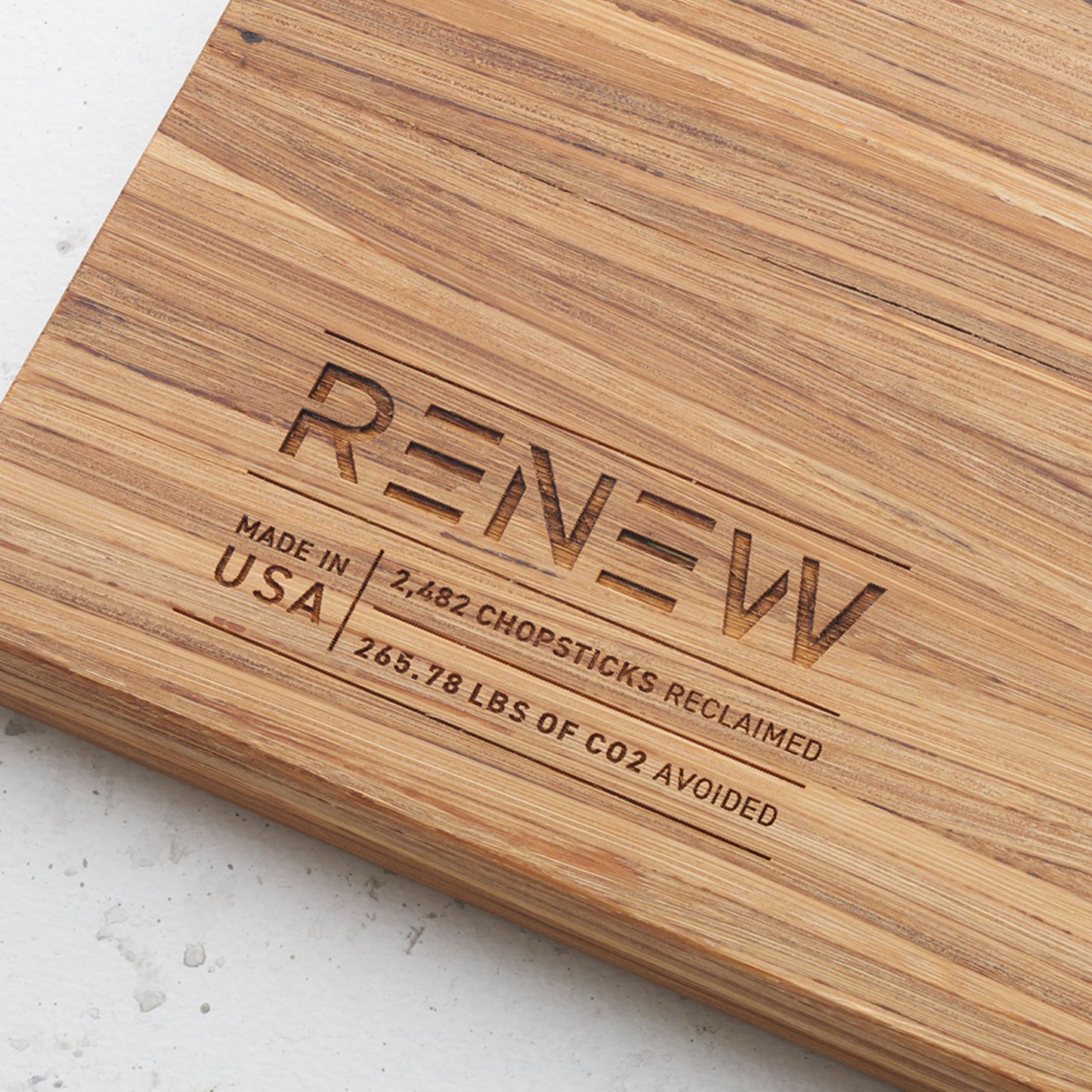 Close up view of the stamp on the back of the board that reads renew made in the usa two thousand four hundred and eighty two chopsticks reclaimed and two hundred and sixty five point seventy eight pounds of co2 avoided
